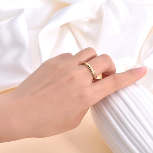 Detail of a rotating gold pyramid stud ring featuring a minimalist geometric pattern