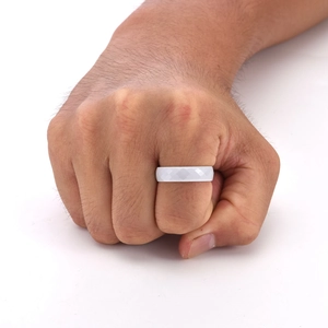 Detail shot of white faceted ceramic ring with diamond-cut surface on male hand