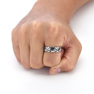 Detailed close-up of a silver titanium steel ring with black geometric crack patterns