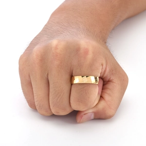Gros plan d'une bague dorée pour homme avec motif géométrique en losange sur fond blanc