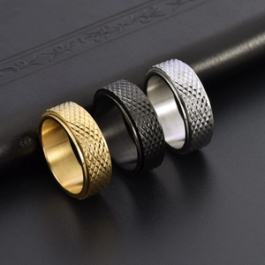 Macro detail of diamond pattern engraved spinning rings in gold, black, and silver steel