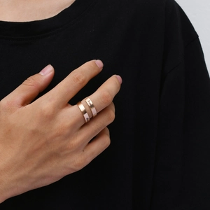 Detail of rose gold titanium steel rings with 'Keep Going' engraving on a model's hand