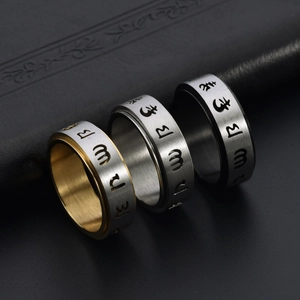 Macro detail of spinning titanium steel rings with mantra engraving in three colors