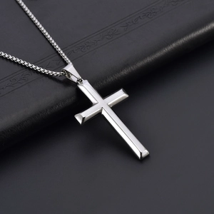 Polished stainless steel cross pendant necklace with box chain on black leather background