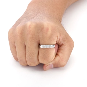 Detailed close-up of a silver tungsten ring featuring geometric diamond cut facets