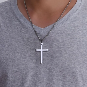 Polished silver stainless steel cross pendant necklace on male model wearing a grey V-neck tee