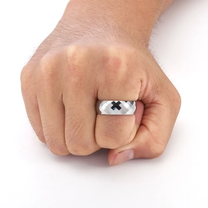 Close-up of a men's faceted tungsten ring with diamond-cut patterns on a hand