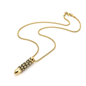 Macro view of gold punk bullet pendant necklace featuring intricate skull pattern engravings