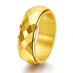 Detail of golden spinner ring with geometric diamond-cut pattern and brushed metal finish