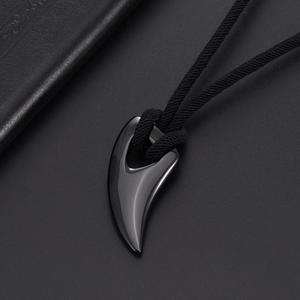 Macro detail of polished black wolf tooth pendant with woven cord on leather surface