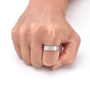 Dettaglio di un anello largo in acciaio al titanio con croce di diamanti sulla mano