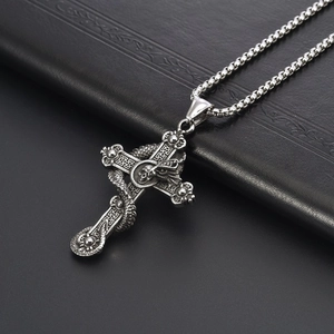 Vintage gothic cross pendant with dragon and skull detail on black leather background