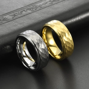 Detail shot of hammered texture tungsten rings in silver and gold on black leather