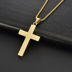Macro shot of gold stainless steel cross pendant featuring engraved Lord's Prayer text
