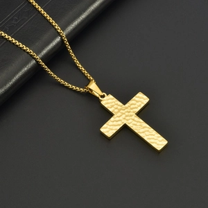 Handmade hammered gold cross pendant necklace for men with a box chain on black surface