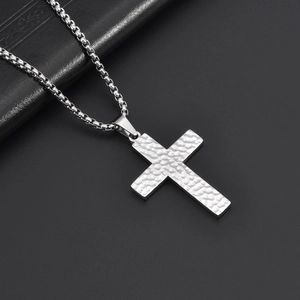 Close-up of silver hammered texture cross pendant on a round box chain necklace