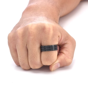 Détail macro d'une bague noire pour homme en titane avec texture de grille à trois rangées