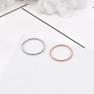 Close-up of minimalist rose gold and silver textured rings on a white display