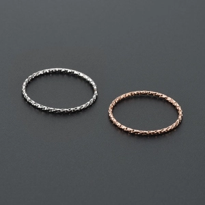 Detail of slim rose gold and silver rings with textured gear embossing and faceted design