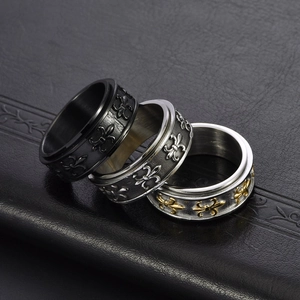Close-up of three vintage gothic rings with fleur-de-lis patterns in black, silver and gold