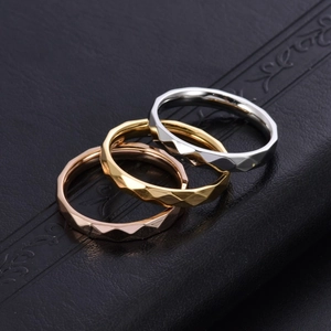 Macro di tre anelli sfaccettati a rombi in argento, oro e oro rosa su pelle nera