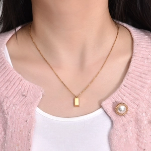 Collier à pendentif barre rectangulaire minimaliste en or présenté sur un mannequin