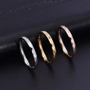 Dettaglio degli anelli a rombi in argento, oro e oro rosa su superficie in pelle