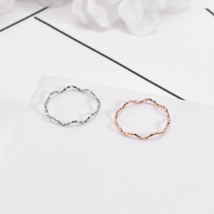 Macro detail of wave-shaped stackable rings in silver and rose gold with hammered texture