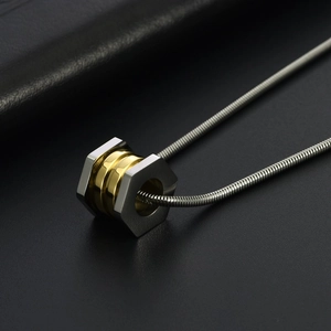 Macro detail of industrial hexagonal nut pendant with two-tone silver and gold metal finish