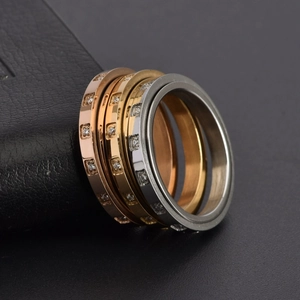 Close-up of rotatable 18K gold plated rings with inlaid crystals on black leather base