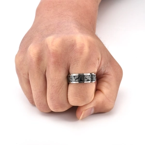 Close-up of rotatable stainless steel ring with black enamel devil eye pattern