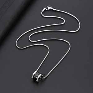 Detailed view of silver titanium steel hexagonal pendant on black leather texture