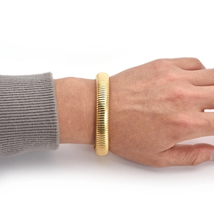 Detailed close-up of a chunky golden spiral textured cuff bracelet worn by a model
