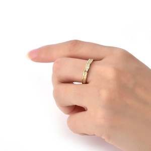 Detail of a minimalist gold eternity band with white zircons worn on a finger
