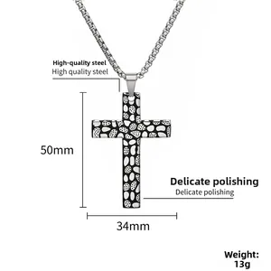 Détail macro du pendentif croix avec texture galet et dimensions en acier titane