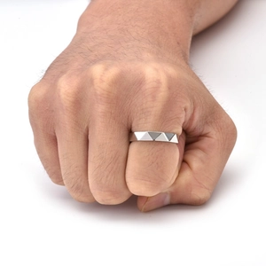 Close-up of men's silver ring with geometric triangle engraving and modern cross pattern