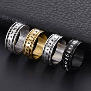 Nordic Rune rings in steel, gold, and black with twisted rope edge on leather backdrop