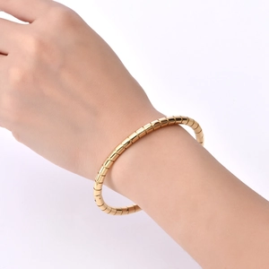 Detailed view of polished 18K gold bamboo style stainless steel bangle worn on wrist