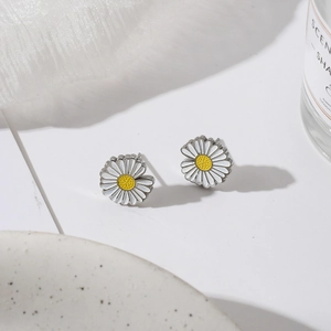 Detailed close-up of daisy stud earrings with white petals on elegant ceramic decor