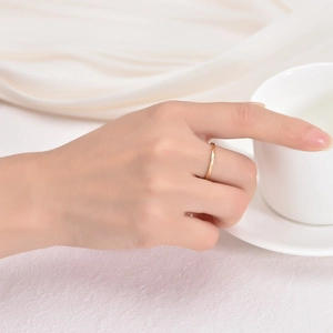 Detail of V-shaped 18K gold ring with geometric triangular facets on hand by coffee cup