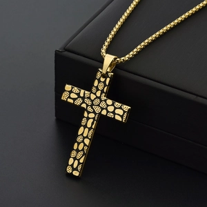 Détail d'un pendentif croix dorée avec émail noir sur une chaîne de type box robuste