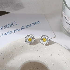 Minimalist white daisy stud earrings in stainless steel on a ceramic tray