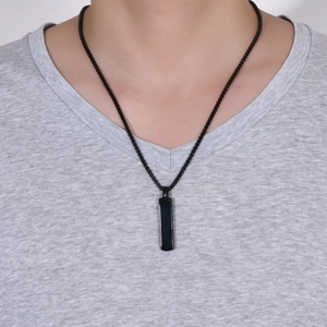 Detail view of a man wearing a sleek black rectangular bar pendant with a bead chain