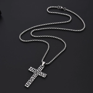 Détail du pendentif croix rétro en acier titane avec texture galet et chaîne box