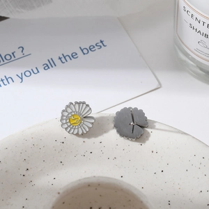 Detail showing white enamel sunflower earrings with yellow centers and silver pins