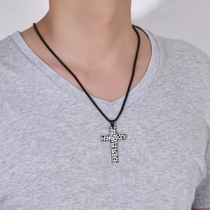 Gros plan d'un pendentif croix vintage avec texture galet sur un mannequin avec chaîne noire