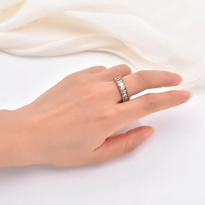 Detailed view of a gold baguette-cut zircon eternity ring worn on a finger