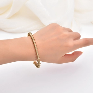 Detailed view of golden spiral cuff bracelet with smooth round beads on a model wrist