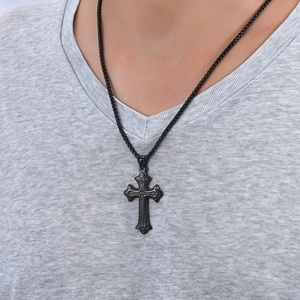 Dettaglio della collana con ciondolo a croce nera e trama a rilievo su maglione lavorato