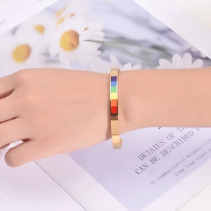 Detail shot of golden C-shaped stainless steel cuff bracelet with rainbow enamel inlay